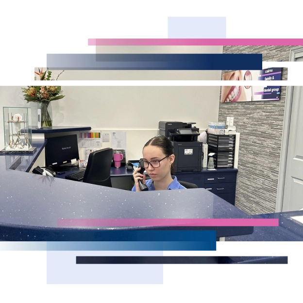 Receptionist on the phone at blue office front desk with computer, flowers, and brochures in a professional setting
