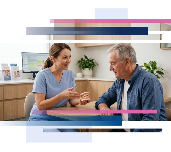 Dentist explaining dental care to an elderly patient while holding a dental model in a modern clinic.