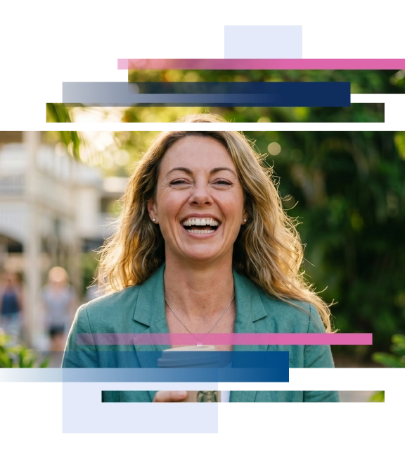 Woman with long hair laughing while holding a coffee cup, surrounded by greenery.